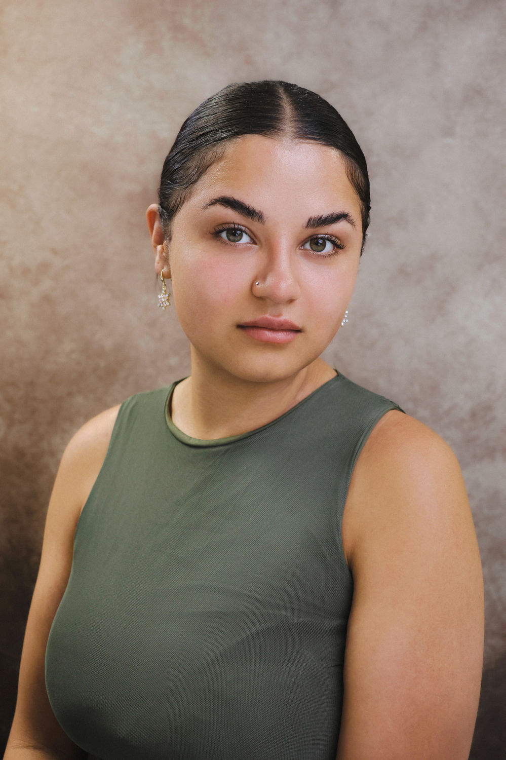 Natural portrait of a woman in a sleeveless green top against a neutral backdrop at a King's Cross portrait studio.